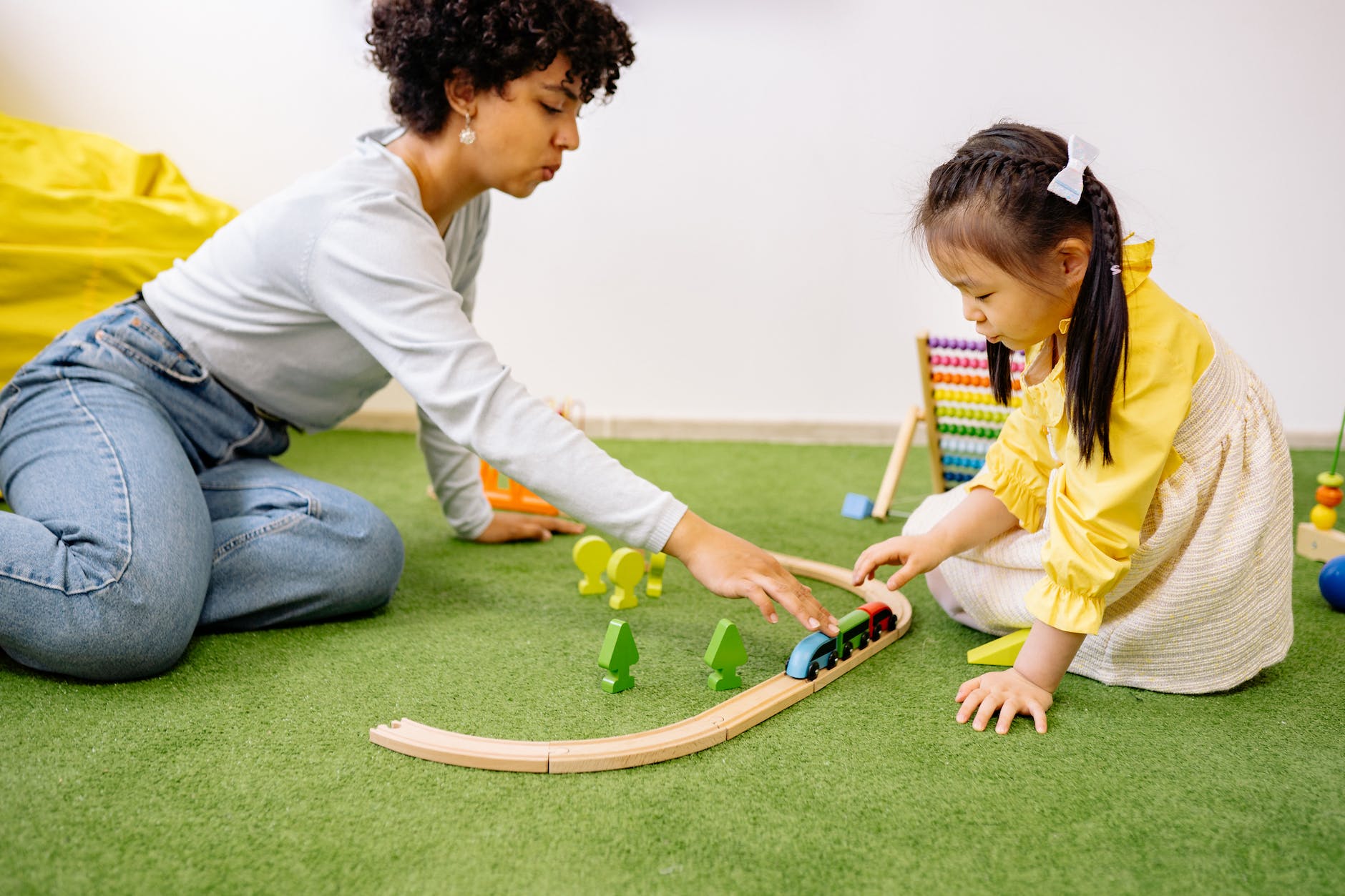 woman playing wooden toy train with a little girl